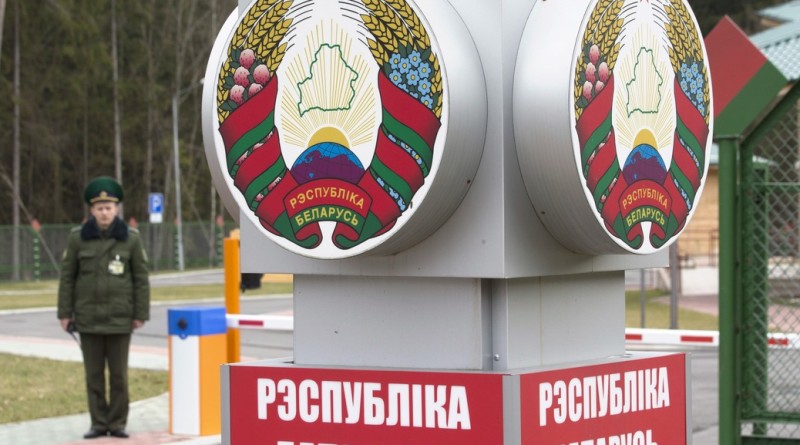 Belarussian border guard stands near a pole with the state emblem, reading, "Republic of Belarus" at a border crossing with Poland near the village of Pererov